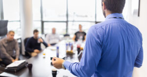 man doing presentation in front of people around a table